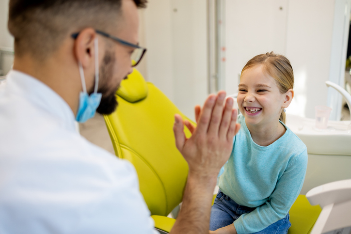 Child smiling at dentist office missing a couple of teeth
