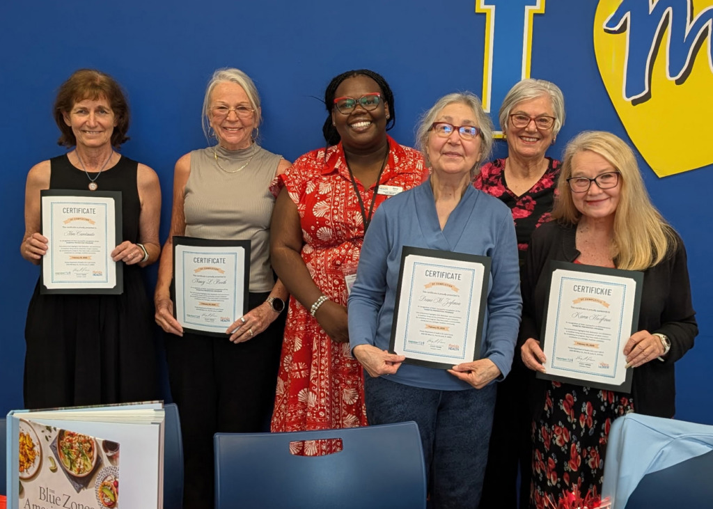 Six smiling participants stand in front of a blue wall, each holding a framed certificate of completion from the Prevent T2D program.